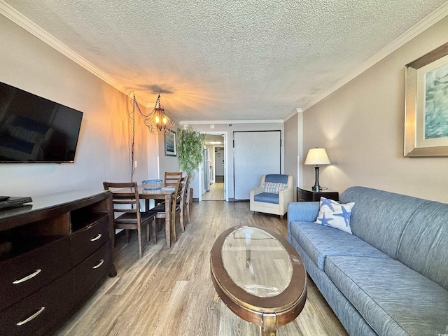 living area featuring ornamental molding, wood finished floors, and an inviting chandelier