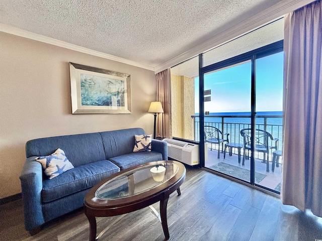 living area with ornamental molding, wood finished floors, a water view, a wall of windows, and a wall mounted AC