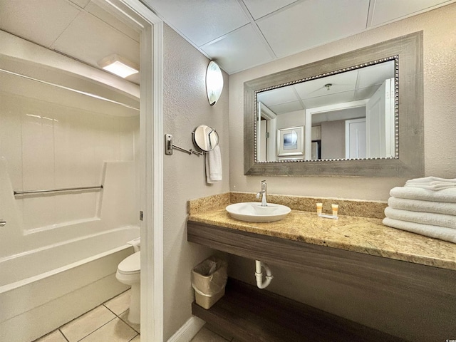 bathroom featuring shower / bath combination, a textured wall, toilet, tile patterned flooring, and a sink