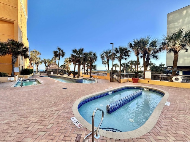 view of pool with a community hot tub and fence