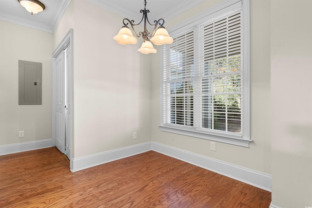 empty room featuring an inviting chandelier, ornamental molding, electric panel, and wood-type flooring