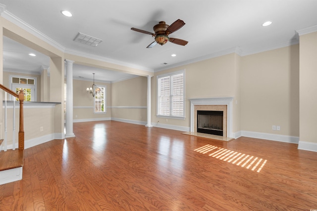 unfurnished living room with ornate columns, crown molding, light wood-type flooring, a fireplace, and ceiling fan with notable chandelier