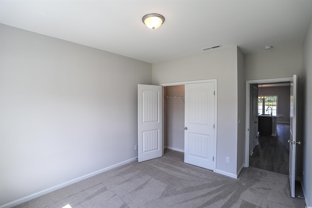 unfurnished bedroom with visible vents, baseboards, carpet, and a closet