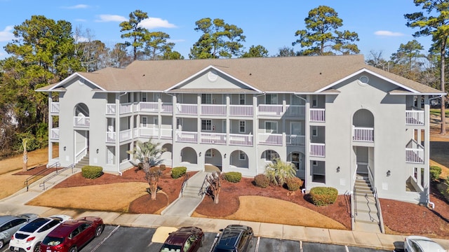 view of building exterior featuring stairs and uncovered parking