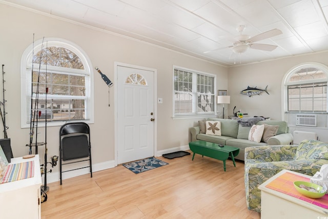 living room with cooling unit, crown molding, ceiling fan, and light wood-type flooring