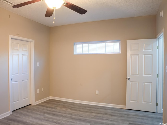 unfurnished room with ceiling fan, hardwood / wood-style flooring, and a textured ceiling