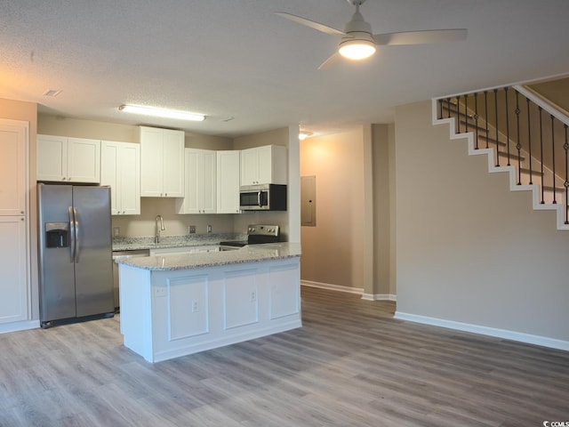 kitchen with light hardwood / wood-style flooring, ceiling fan, stainless steel appliances, light stone countertops, and white cabinets