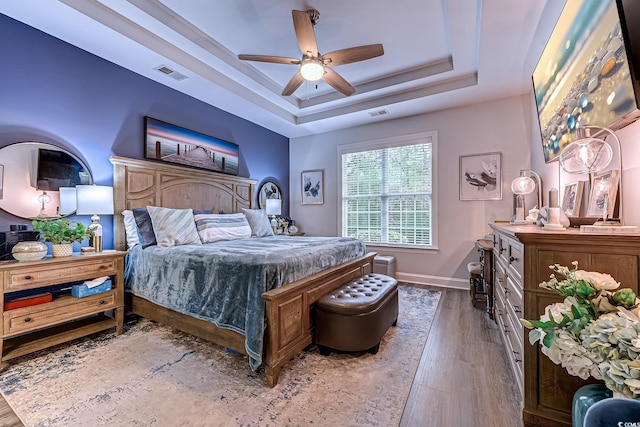 bedroom with a raised ceiling, hardwood / wood-style floors, and ceiling fan