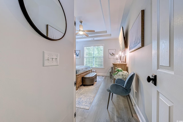 bathroom with ceiling fan, a tray ceiling, and hardwood / wood-style floors