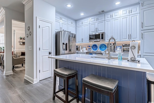 kitchen featuring appliances with stainless steel finishes, a breakfast bar, sink, and light hardwood / wood-style flooring