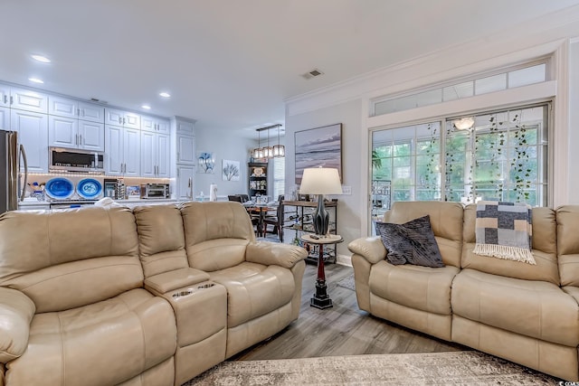 living room featuring crown molding and light hardwood / wood-style floors