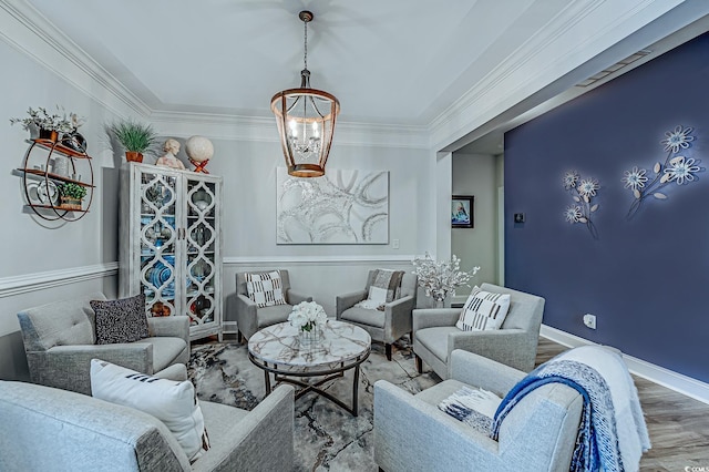 living room with an inviting chandelier, ornamental molding, and wood-type flooring