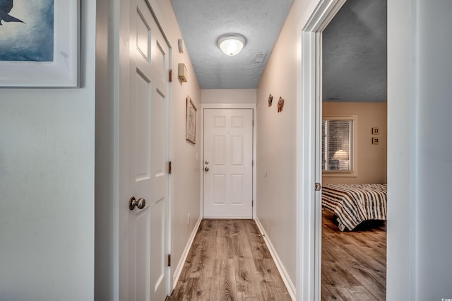 corridor featuring light hardwood / wood-style floors and a textured ceiling