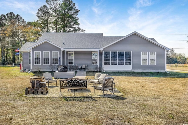 back of house featuring a lawn and an outdoor living space with a fire pit