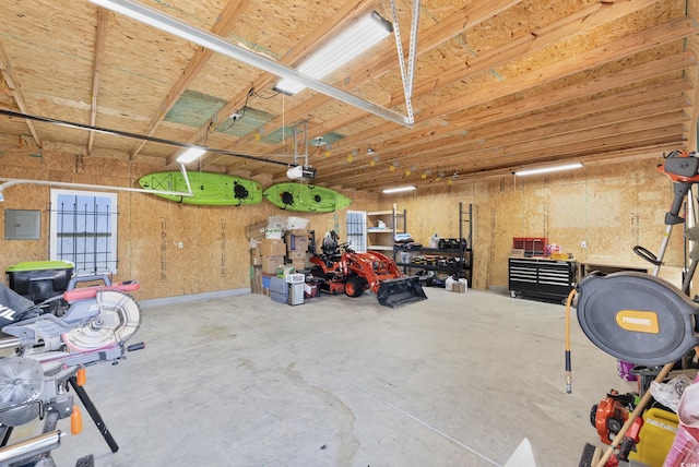 garage with a garage door opener, electric panel, and a workshop area