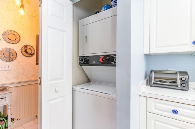 clothes washing area with laundry area, stacked washer and dryer, and wainscoting