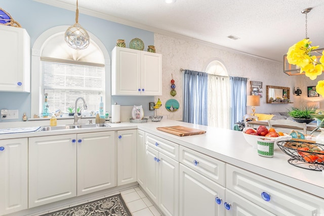kitchen with visible vents, ornamental molding, light countertops, a sink, and decorative light fixtures