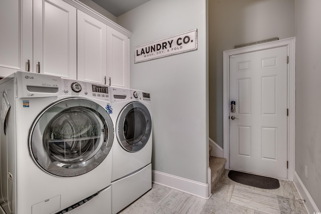 clothes washing area with cabinets and washing machine and dryer