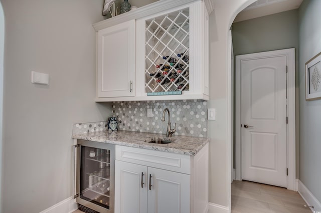 bar with wine cooler, sink, and white cabinets