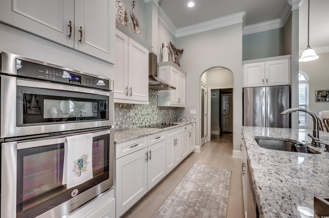 kitchen with appliances with stainless steel finishes, sink, white cabinets, hanging light fixtures, and light stone counters