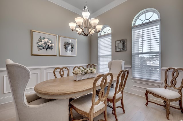 dining area featuring light hardwood / wood-style flooring, ornamental molding, and a chandelier