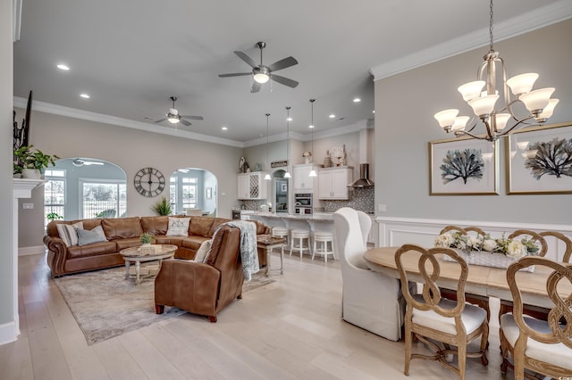 living room with ornamental molding, ceiling fan with notable chandelier, and light hardwood / wood-style flooring