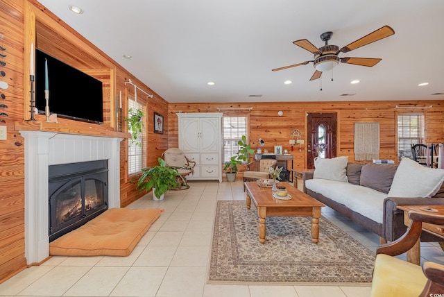 living room with light tile patterned floors, wooden walls, and ceiling fan