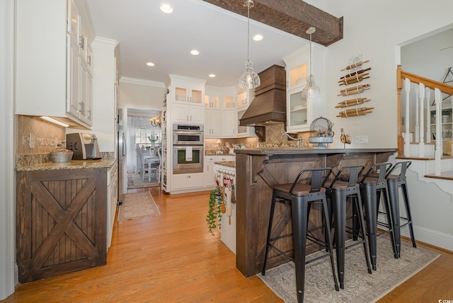 kitchen with a breakfast bar area, appliances with stainless steel finishes, kitchen peninsula, pendant lighting, and white cabinets