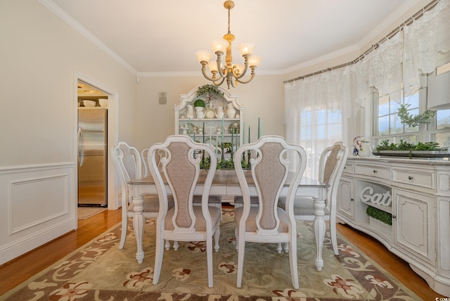 dining room with an inviting chandelier, crown molding, and light wood-type flooring