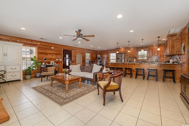 living room with light tile patterned floors, ceiling fan, and wood walls