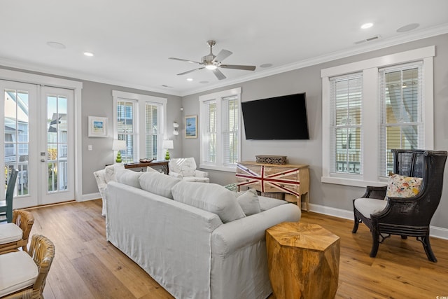 living area with ornamental molding, french doors, and light wood-style floors