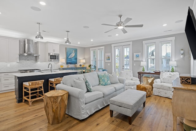 living area with light wood-type flooring, ceiling fan, crown molding, and recessed lighting