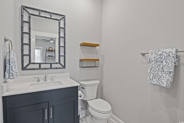 half bathroom featuring baseboards, vanity, and toilet