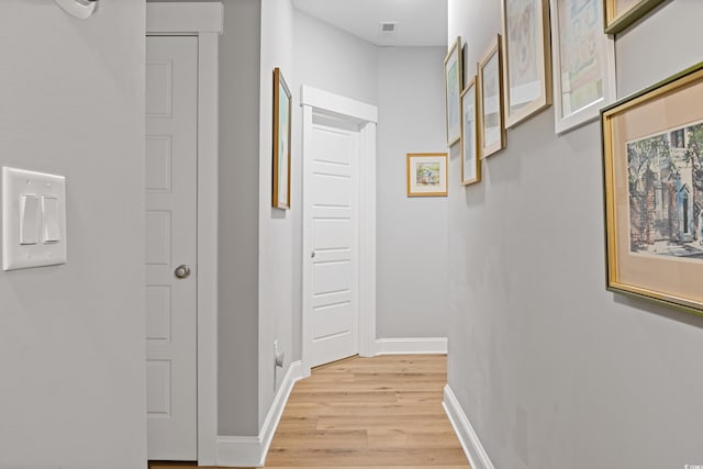 hallway featuring baseboards, visible vents, and light wood-style floors