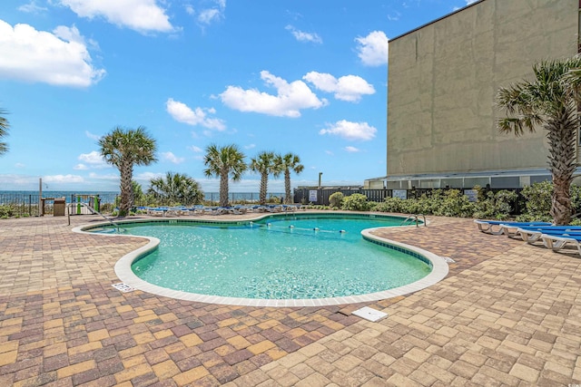 view of swimming pool featuring a patio and a water view