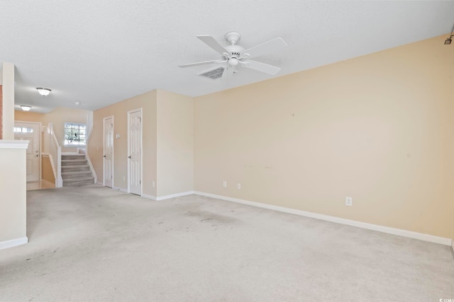 empty room featuring ceiling fan, light colored carpet, and a textured ceiling