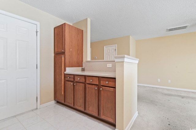 kitchen featuring light tile patterned flooring, kitchen peninsula, and a textured ceiling