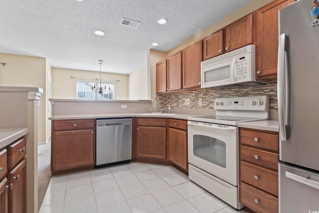 kitchen featuring sink, light tile patterned floors, stainless steel appliances, decorative backsplash, and decorative light fixtures