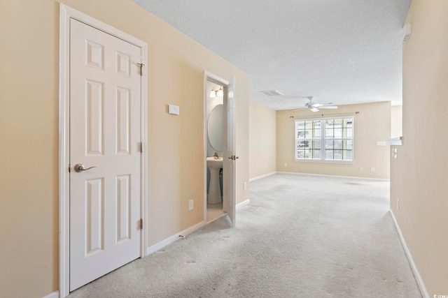 hall with light carpet and a textured ceiling