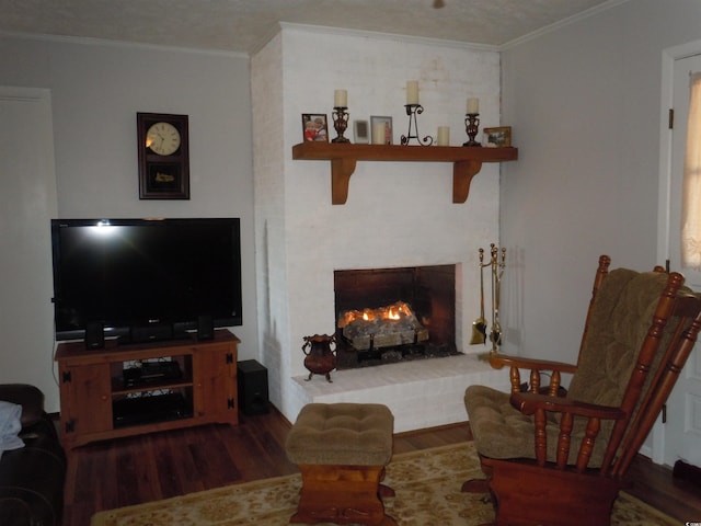 living room featuring dark hardwood / wood-style flooring, a brick fireplace, and ornamental molding