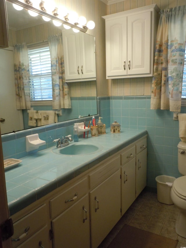 bathroom with vanity, toilet, tile patterned flooring, and tile walls