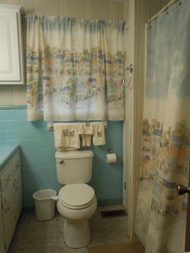 bathroom featuring tile patterned flooring, walk in shower, vanity, and toilet