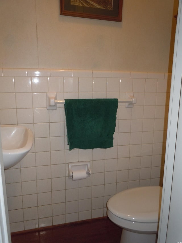 bathroom featuring sink, tile walls, and toilet