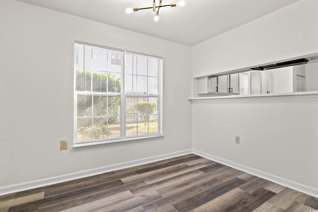 empty room featuring dark hardwood / wood-style floors, a chandelier, and a textured ceiling