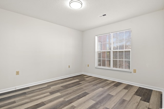 unfurnished room featuring hardwood / wood-style floors and a textured ceiling