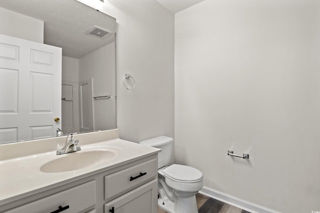 bathroom featuring vanity, toilet, wood-type flooring, and a textured ceiling