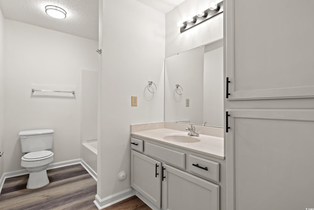 full bathroom with toilet, shower / bathing tub combination, a textured ceiling, vanity, and hardwood / wood-style flooring