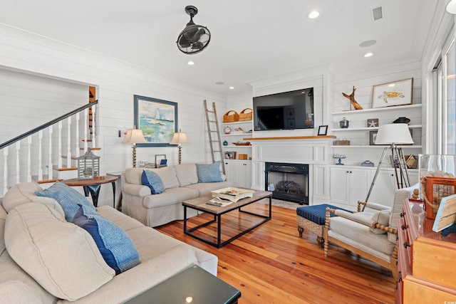 living room with ornamental molding and light hardwood / wood-style flooring