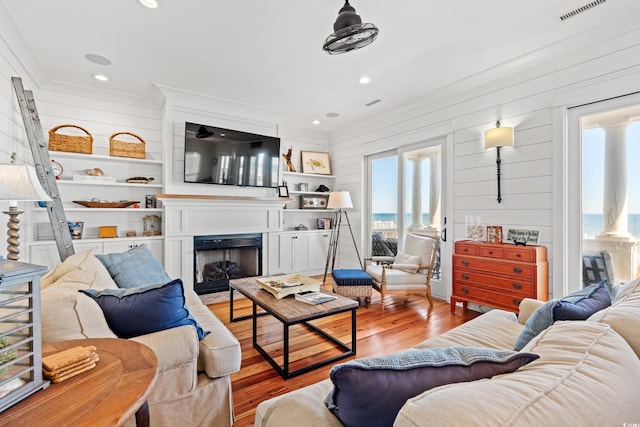 living room with ornamental molding, wood walls, and light wood-type flooring