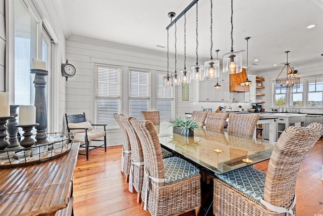 dining space with a notable chandelier, crown molding, and light hardwood / wood-style flooring